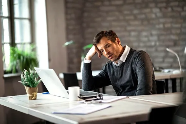 Homme fatigué devant son ordinateur au bureau.