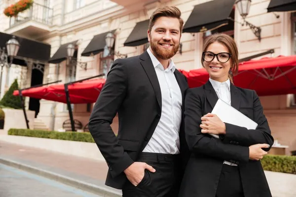 Deux personnes en tenues professionnelles souriantes.