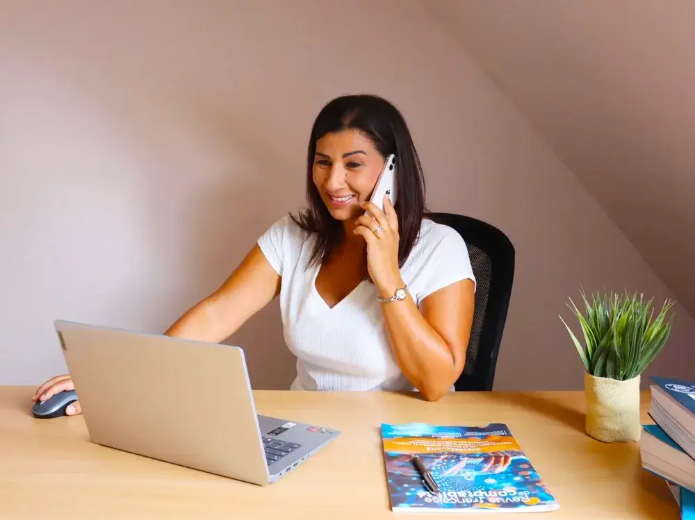 Sofia de l'équipe Ilyara, souriante au téléphone devant son ordinateur